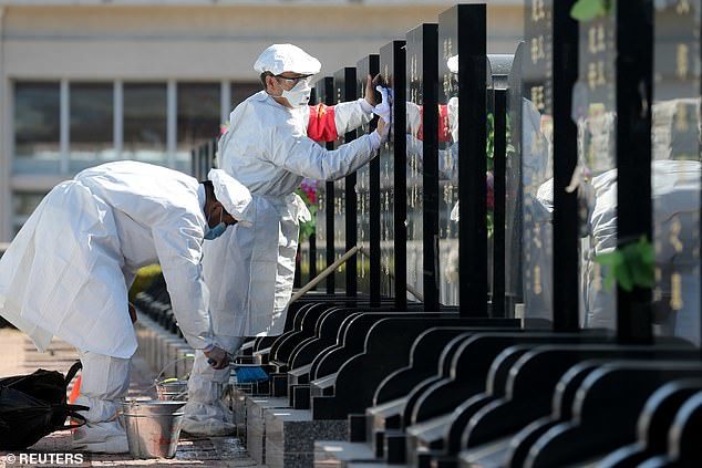  
Nhân viên mặc trang phục bảo hộ quét dọn bia mộ thay cho các gia đình theo yêu cầu từ Chính quyền địa phương. (Ảnh: Reuters)