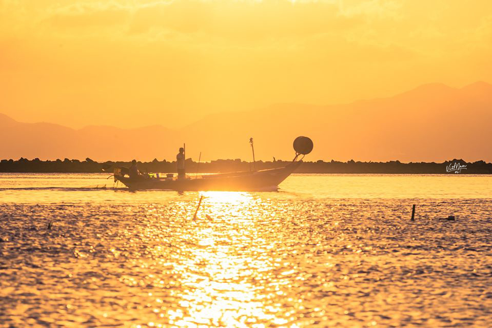  
Chiếc thuyền ngoài xa lấp lánh trong ánh nước, quyện với màu cam cháy từ mặt trời khiến người ta cảm thấy xuyến xao và khao khát một lần trải nghiệm ra khơi. (Ảnh: Phạm Ngọc Tuấn)