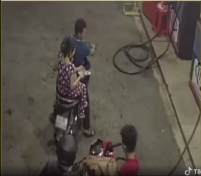  
Người phụ nữ chuẩn bị tiền trả khi anh nhân viên đang đổ cho một xe khác. (Ảnh: Cắt từ clip)