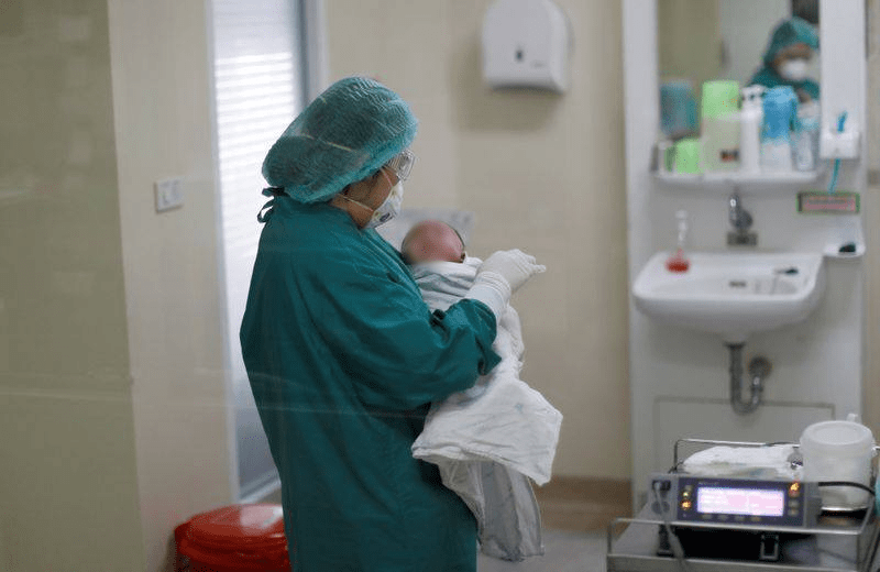  
Các y bác sĩ chăm sóc cho các em bé sơ sinh giữa mùa dịch Covid-19. (Ảnh: Reuters).