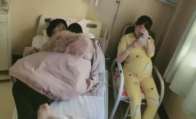  
Trong khi chị vợ ngồi ghế thì anh chồng lại ngủ ngon lành trên giường bệnh. (Ảnh: Sina)