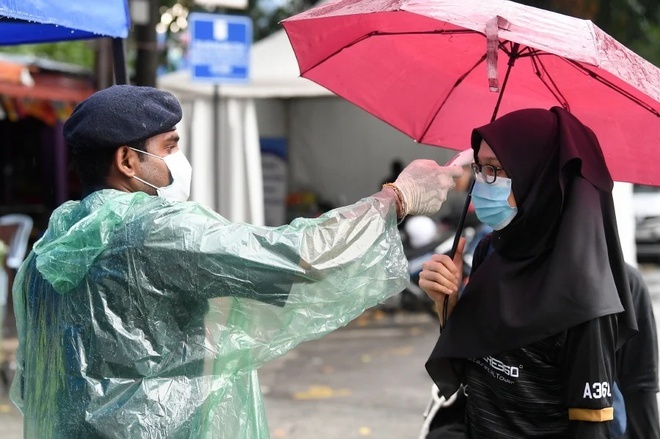  
Cảnh sát Malaysia kiểm tra thân nhiệt của mọi người ở trạm kiểm soát (Ảnh: Bernama)