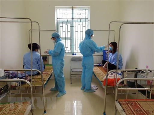 
Nhân viên y tế kiểm tra sức khỏe cho 2 du học sinh (Ảnh: TTXVN)
