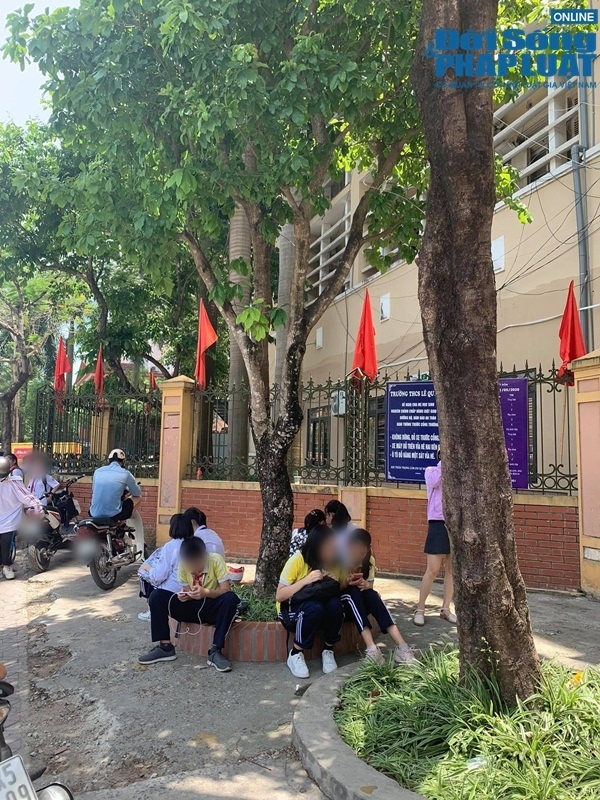  
Các em học sinh ngồi chờ bố mẹ dưới tán cây để tránh nắng (Ảnh: Đời sống & Pháp luật)