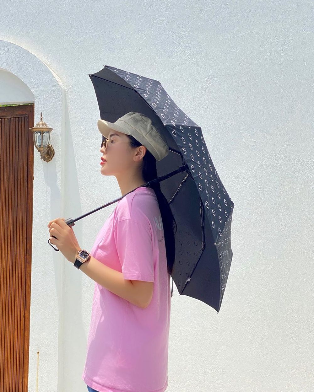  
Kỳ Duyên tránh cái nóng mùa hè với chiếc áo thun hồng đơn giản. Nàng Hậu đội nón, đeo mắt kính và cầm thêm dù xuống phố. (Ảnh: Instagram nhân vật)