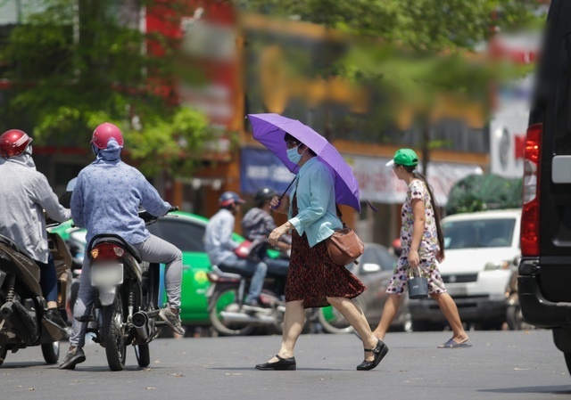  
Người phụ nữ mặc áo chống nắng, che ô khi đi ra đường (Ảnh: Dân Trí)