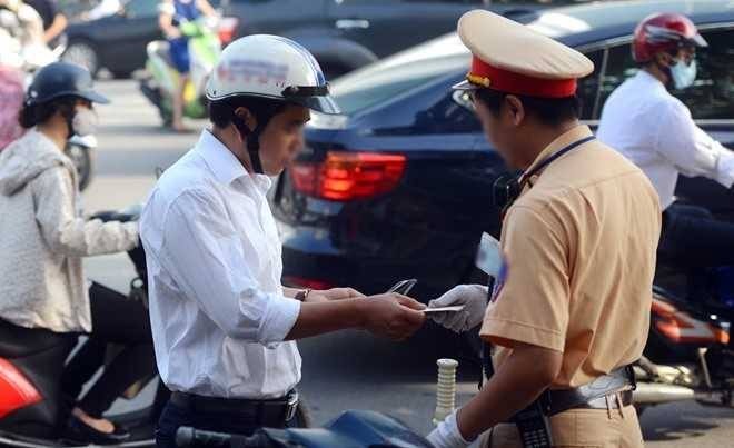  
Cảnh sát giao thông kiểm tra giấy tờ của người điều khiển xe máy. (Ảnh: Luật Việt Nam)