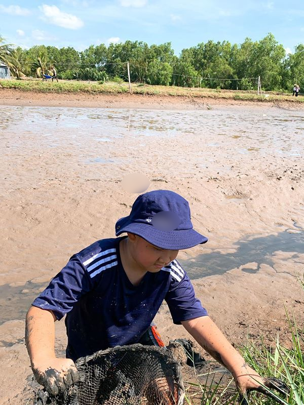  
Cà Pháo thích thú lội sình để bắt cá giữa trời nắng. Đây không phải là trải nghiệm mà đứa trẻ nào cũng có được. (Ảnh: FBNV) - Tin sao Viet - Tin tuc sao Viet - Scandal sao Viet - Tin tuc cua Sao - Tin cua Sao