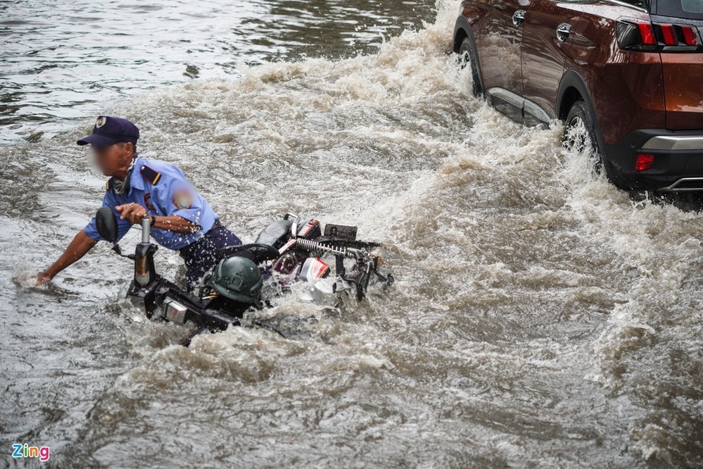  
Một người đi xe máy ngã nhào vì đường ngập (Ảnh: Zing)