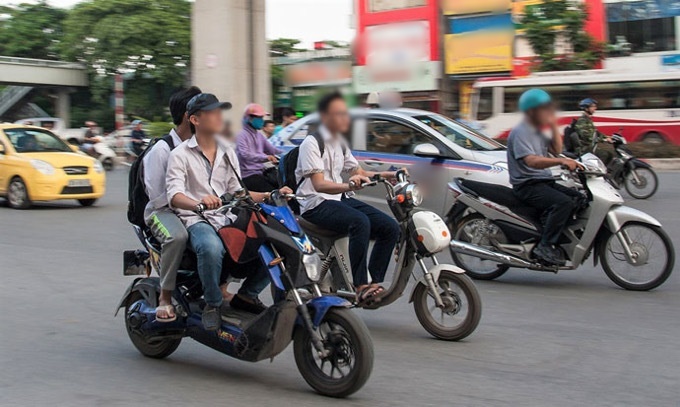  
Học sinh đi xe đạp điện không đội mũ bảo hiểm trên đường (Ảnh: Thanh Niên)