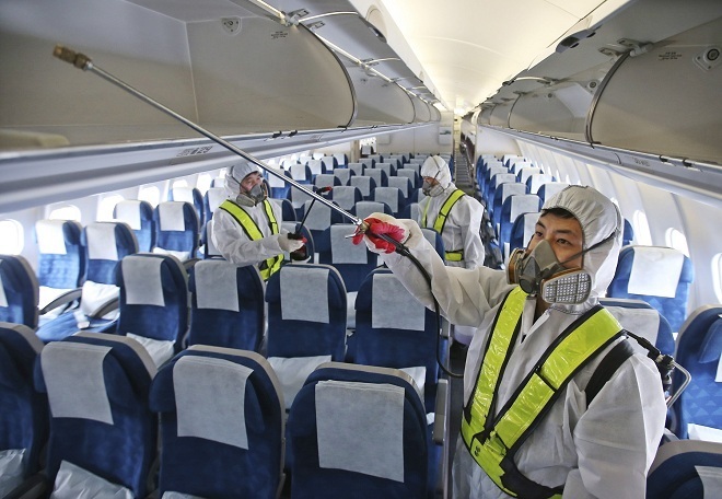  
Nhân viên y tế tiến hành xịt khuẩn máy bay. (Ảnh: The New York Times)