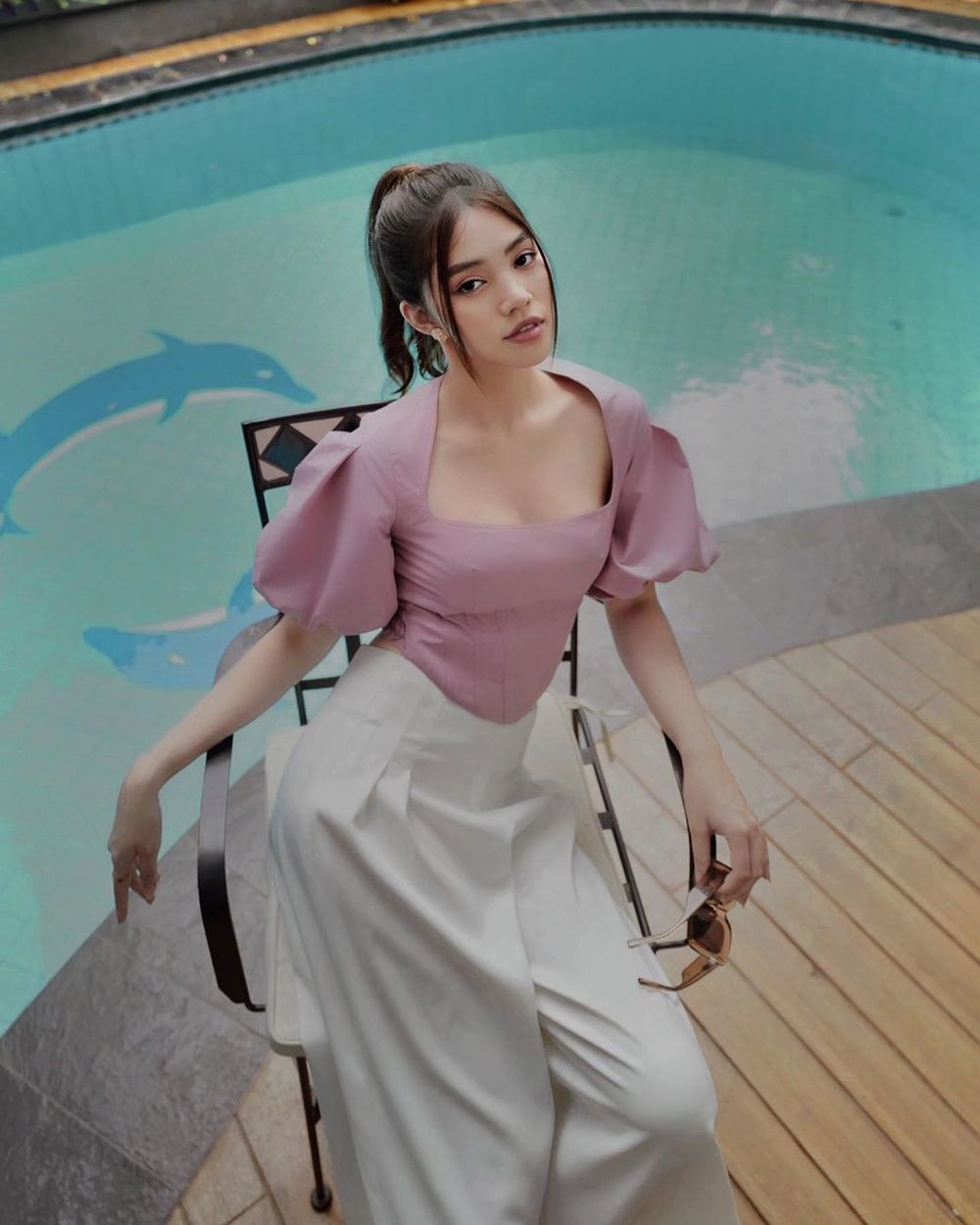  
"Rich kid" Jolie Nguyễn nhẹ nhàng với áo tím pastel, quần ống suông thả dáng bên hồ bơi. (Ảnh: FBNV)