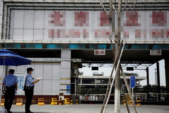  
Cảnh sát đứng canh gác tại cổng của khu chợ Tân Phát Địa - nơi bùng phát dịch ở Bắc Kinh (Ảnh: Reuters)