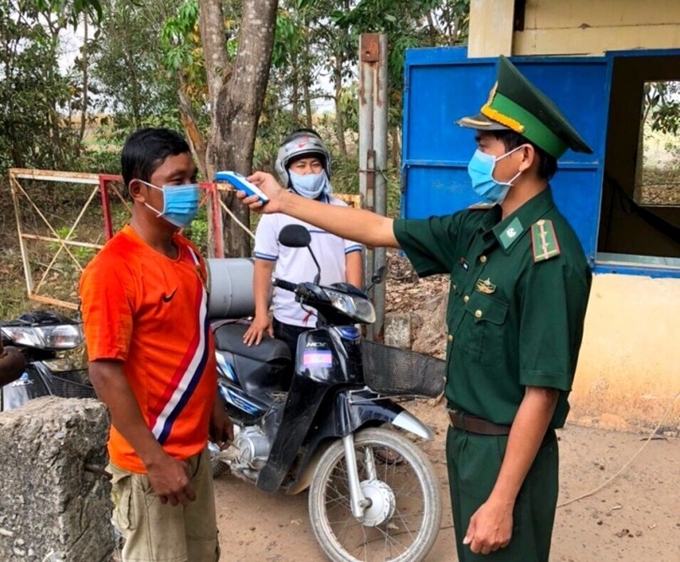  
Cán bộ đồn biên phòng ở Tây Ninh đo thân nhiệt cho người qua cửa khẩu (Ảnh: Báo Tây Ninh)