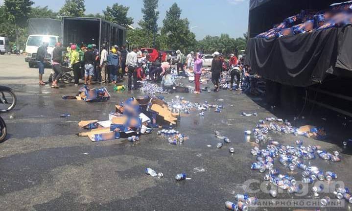 Nhiều người hỗ trợ chuyển bia từ xe tải gặp nạn sang xe tải khác (Ảnh: Báo Công an TP.HCM)