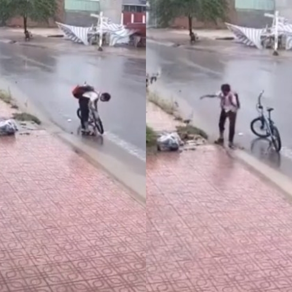  
Đ. dừng xe giữa trời mưa để nhặt rác khơi thông miệng cống (Ảnh: Chụp màn hình)