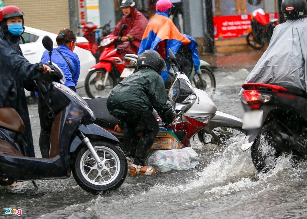  
Một người đi xe máy bị đổ xe do mưa ngập (Ảnh: Zing)
