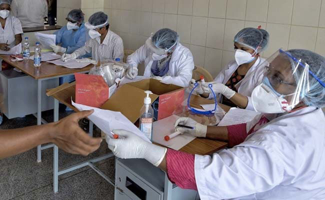  
Nhân viên y tế đưa giấy và hướng dẫn mọi người khi xét nghiệm (Ảnh: NDTV)