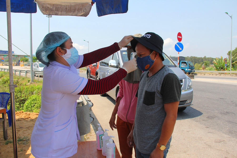  
Nhân viên y tế kiểm tra thân nhiệt 1 lái xe đường dài đi xe vào địa bàn tỉnh Quảng Nam (Ảnh: Công an Nhân dân)