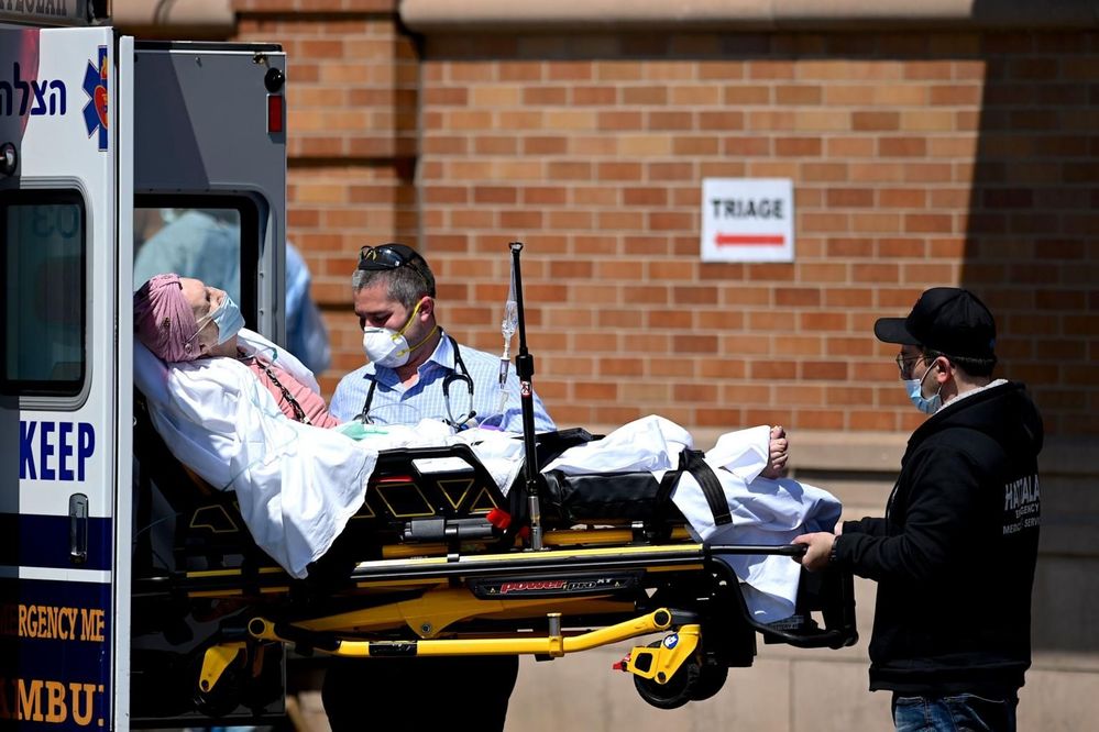  
Nhân viên y tế đang đưa bệnh nhân nhiễm Covid-19 đến bệnh viện để điều trị. (Ảnh: AFP)