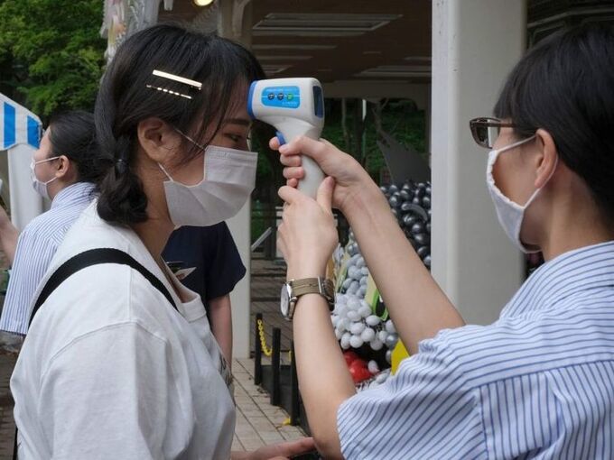  
Kiểm tra thân nhiệt cho mọi người trước khi vào công viên tại Nhật Bản. (Ảnh: Reuters)