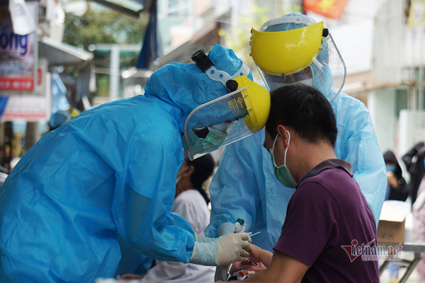  
Nhân viên y tế lấy mẫu xét nghiệm cho mọi người (Ảnh: Vietnamnet)