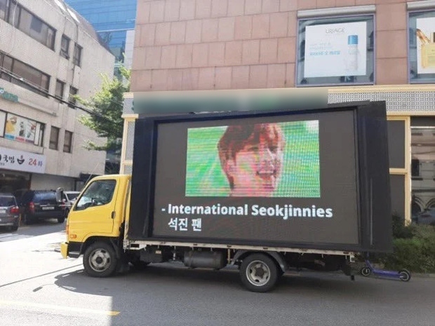 
Fan quốc tế gửi xe tải đến trước công ty Big Hit. Ảnh: Twitter