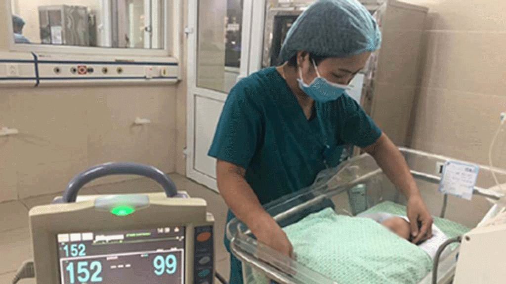  
Nhân viên y tế tại bệnh viện chăm sóc cho bé trai (Ảnh: Thanh Niên)