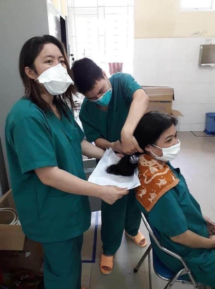 Các nữ bác sĩ, điều dưỡng làm việc cắt tóc cho nhau,để thuận lợi khi điều trị bệnh nhân Covid-19. (Ảnh: VnExpress)