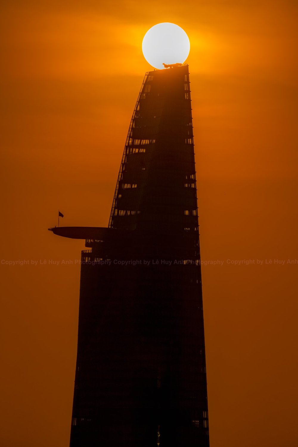  
Hình ảnh mặt trời nằm trên đỉnh tòa tháp Bitexco. 