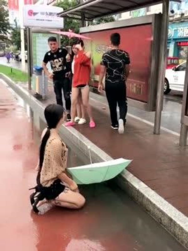  
Chàng trai để lại ô cho cô gái rồi cất bước ra đi. (Ảnh: Dongfang)