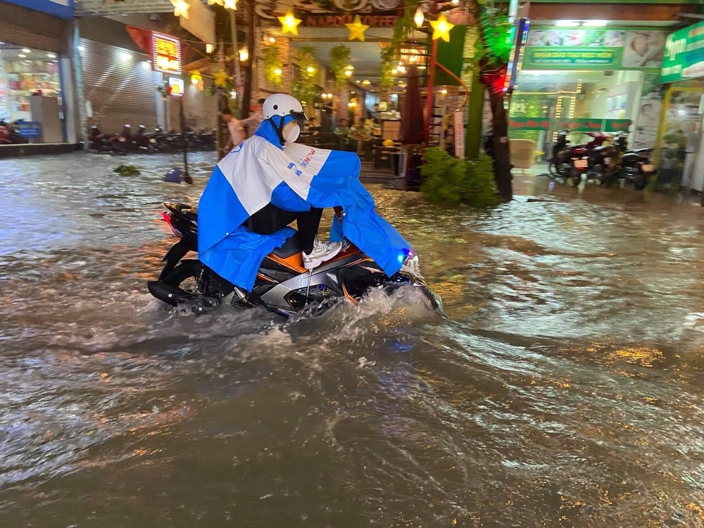
Một người lội nước trở về nhà sau cơn mưa chiều (Ảnh: 24h)