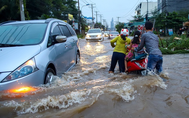  
Người dân di chuyển khó khăn trên một tuyến đường bị ngập nước ở TP.HCM. (Ảnh: Zing)