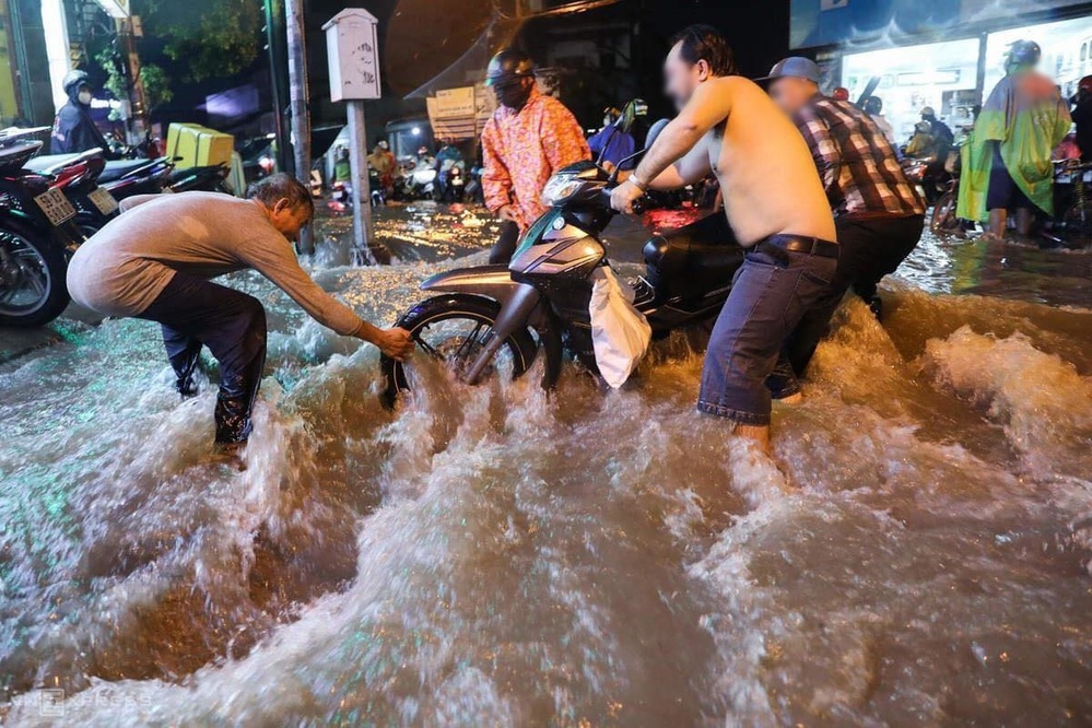  
Mọi người giúp cô gái kéo xe qua đoạn nước chảy xiết (Ảnh: VNExpress)