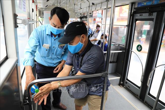  
Một nhân viên xe buýt đang hướng dẫn hành khách rửa tay để phòng dịch. (Ảnh: TTXVN)