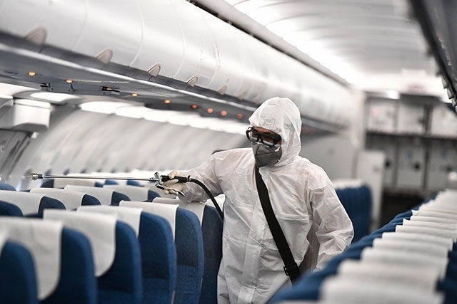 
Nhân viên y tế phun khử trùng máy bay để đảm bảo an toàn (Ảnh: VNA)