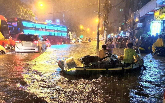 
Mọi người vận chuyển đồ đạc khi xảy ra mưa, ngập lớn. (Ảnh: Thanh Niên)