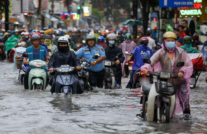  
Nước ngập làm hư máy xe, người dân phải dắt bộ trong giờ tan tầm. (Ảnh: Thanh Niên)