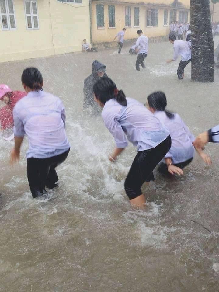  
Học sinh lạc quan đến trường dù mưa bão. (Ảnh: Tiền phong)