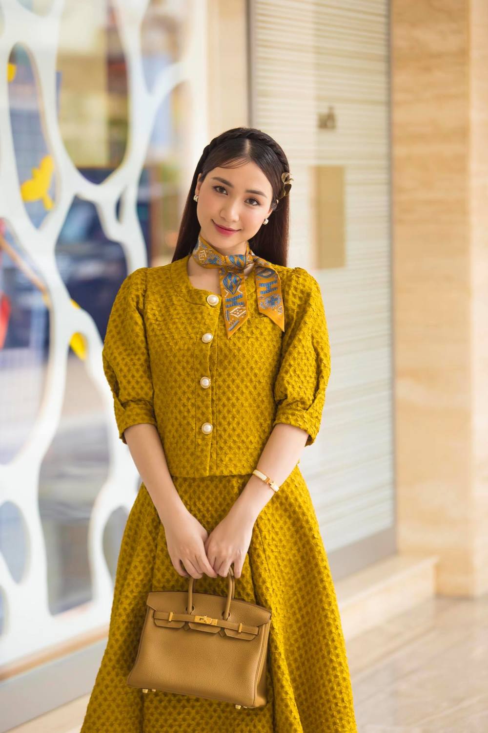  
Hòa Minzy đeo túi hiệu 400 triệu tông vàng với bộ cánh cổ điển đồng màu. (Ảnh: FBNV)