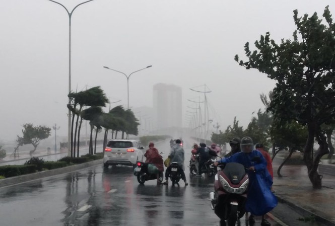  
Người dân di chuyển khó khăn trong mưa bão. (Ảnh: Tiền Phong).