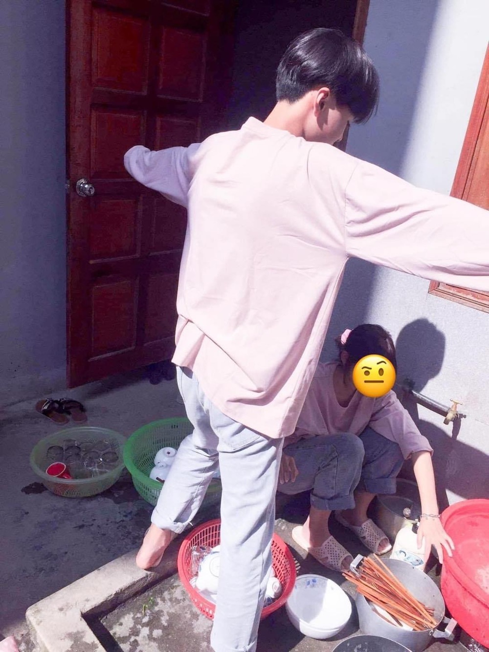 
Hình ảnh chàng trai "quan tâm" che nắng cho cô bạn gái ngồi rửa bát gây tranh cãi. (Ảnh: H.T)