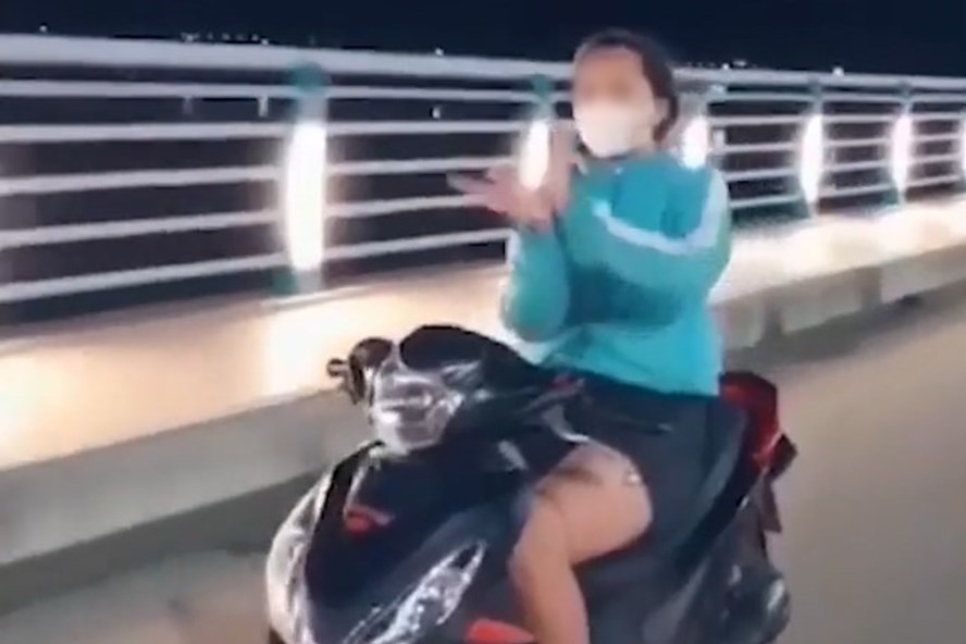 
Hình ảnh cô gái thả hai tay múa quạt khi đang điều khiển xe (Ảnh: Cắt từ clip)