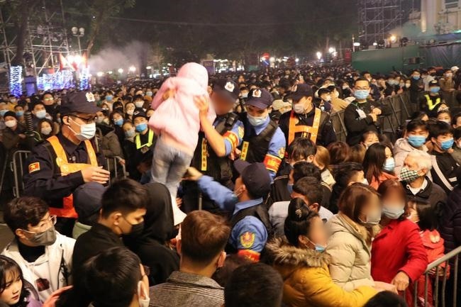  
Lực lượng chức năng bế một cháu bé ra khỏi đám đông hỗn loạn trong đêm 31/12/2020 (Ảnh: Dân Việt)