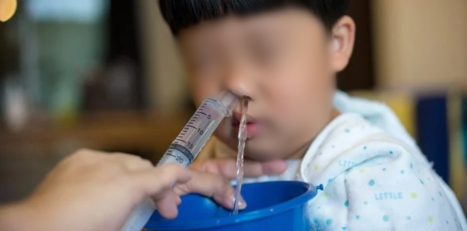  
Một bé trai được rửa mũi bằng nước muối (Ảnh: Meta)