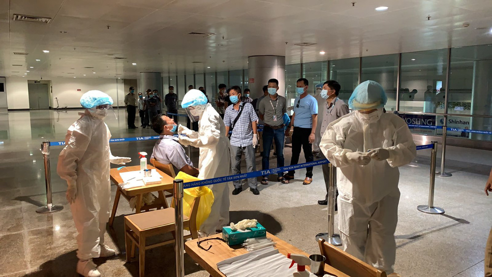  
Nhân viên y tế lấy mẫu xét nghiệm cho hành khách tại sân bay Tân Sơn Nhất. (Ảnh: Người Lao Động)