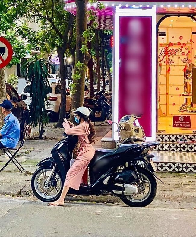  
Cô gái xoạc chân chống xe máy. (Ảnh: T.H)