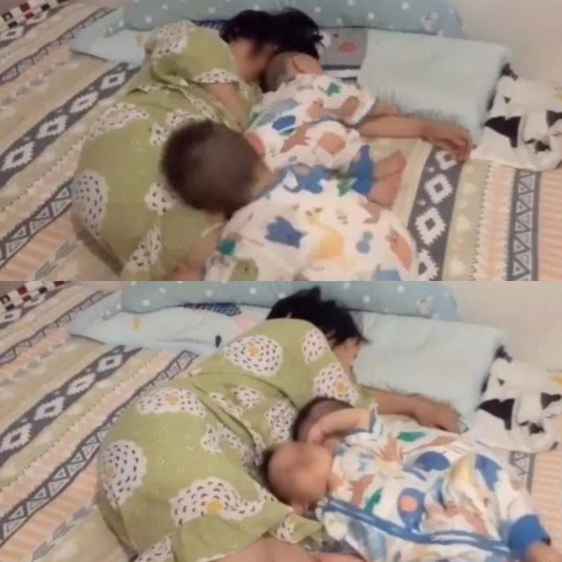  
Người mẹ ngủ thiếp đi bên 2 con vì mệt. (Ảnh: Cắt từ clip)