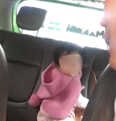  
Bé gái thơ ngây chỉ khoảng hơn 1 tuổi, ngồi chơi phía sau xe đợi mẹ. (Ảnh: Chụp màn hình)