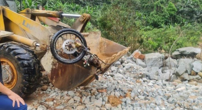  
Một chiếc xe máy bị vùi dưới lớp đất đá được đưa ra ngoài. (Ảnh: Lao Động)